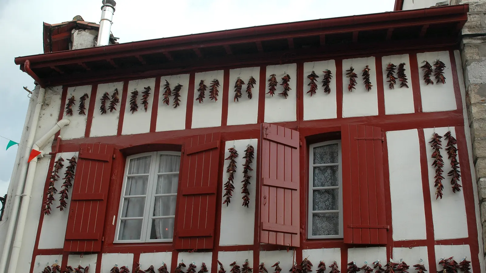 Façade à colombages rouges d'Espelette où sèchent des cordes de piments